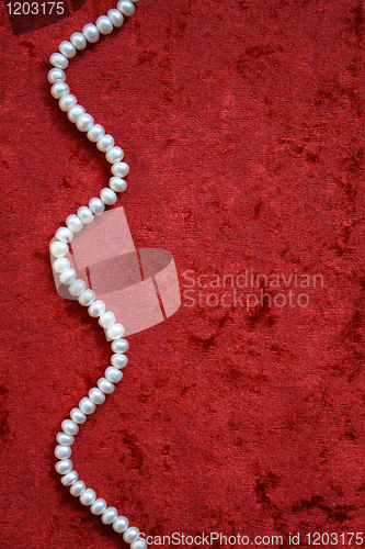 Image of Necklace of white pearls on a terracotta velvet background 