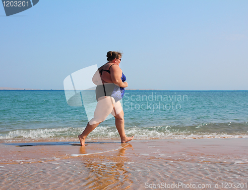 Image of overweight woman running on beach
