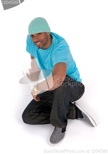 Image of Relaxed young man in a blue t-shirt sitting on the floor