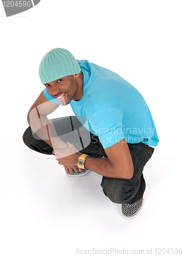 Image of Smiling young man in a blue t-shirt squatting