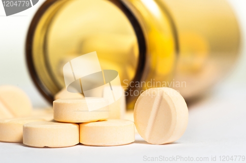 Image of Pills on whhite floor with bottle in the background