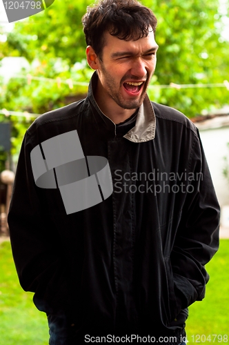 Image of Young man laughing on a joke outdoors