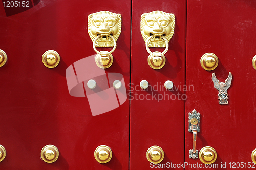 Image of Red door decorated with golden door knobs