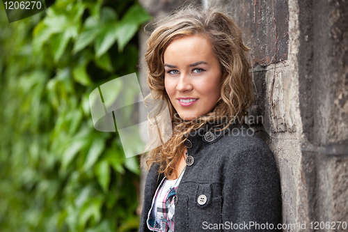 Image of Casual woman standing against stone wall