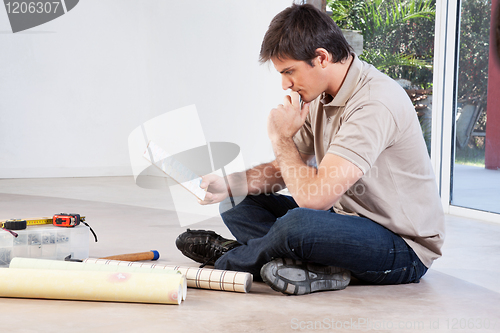 Image of Man sitting on floor and going through color swatch