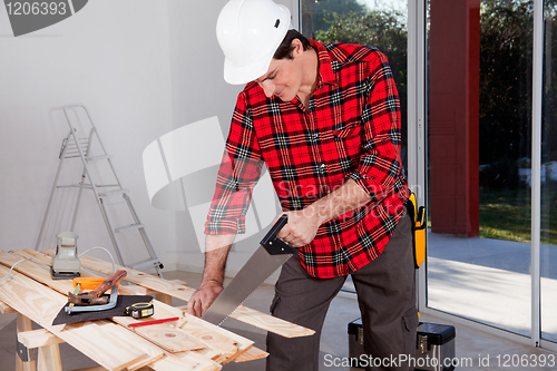 Image of Construction Worker Using Hand Saw