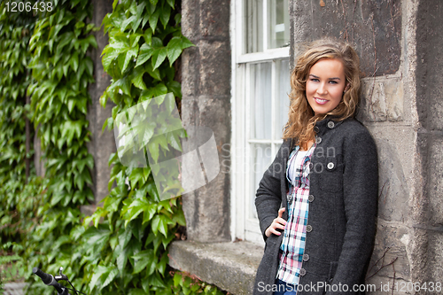 Image of Blond woman leaning against stone wall