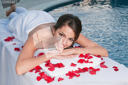 Image of Smiling young woman at spa with rose petals around
