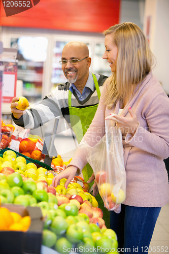 Image of Happy young woman buying fruits