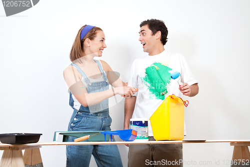 Image of Happy woman having fun coloring her boyfriend's shirt