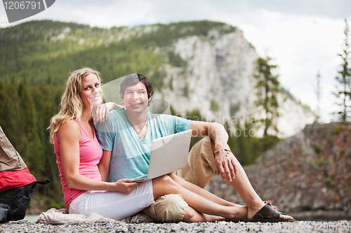 Image of Relaxed couple with laptop while camping