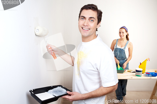 Image of Smiling man painting the wall of his new apartment