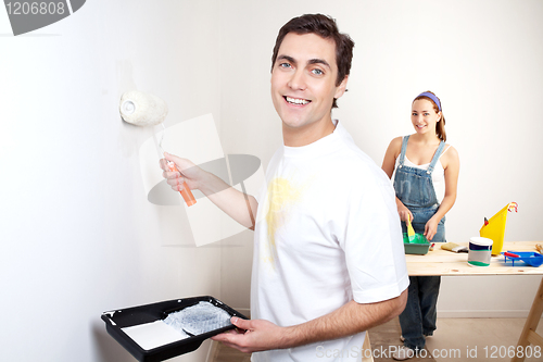 Image of Smiling man painting the wall of his new apartment