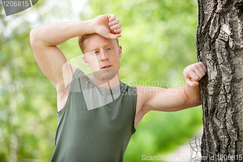 Image of Tired man leaning on tree