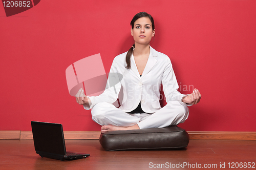 Image of Businesswoman sitting in yoga lotus position