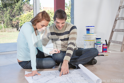 Image of Man showing blueprint of their new house to his wife