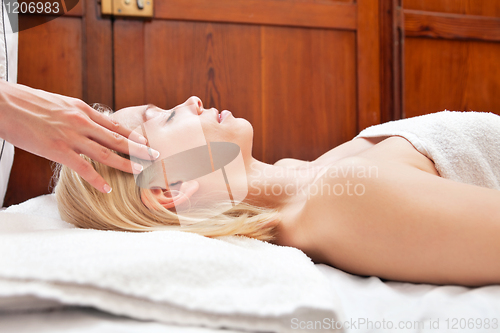 Image of Young blond woman receiving head massage