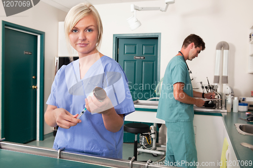 Image of Nurse with syringe while doctor writing report