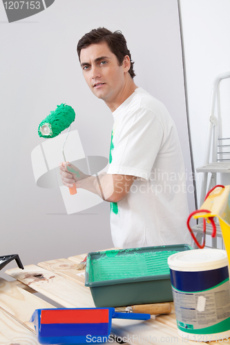 Image of Casual man holding a roller paint brush