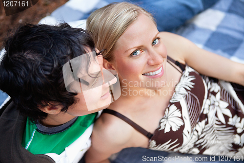 Image of Young couple relaxing on picnic blanket