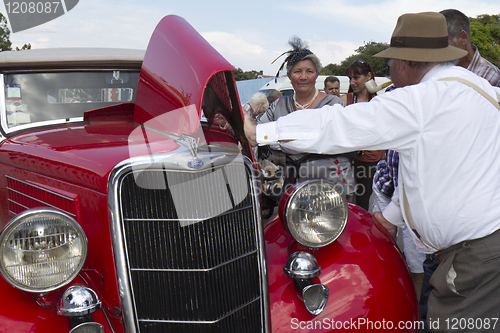 Image of People looking at an old automobile.