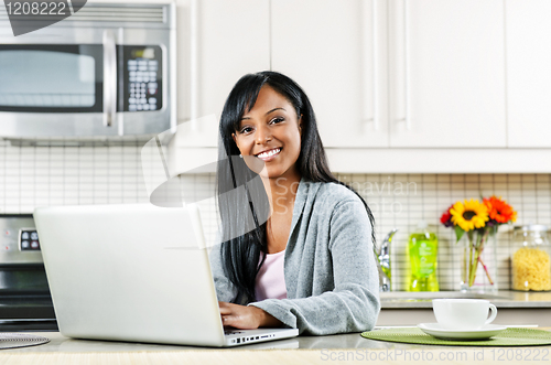 Image of Woman using computer in kitchen