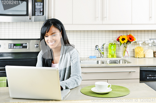 Image of Woman using computer in kitchen