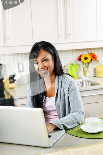 Image of Woman using computer in kitchen