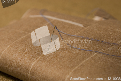 Image of needle and thread on fabric background
