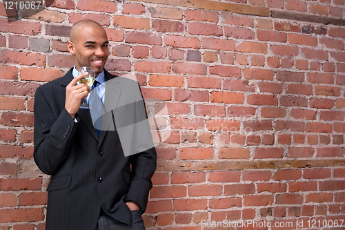Image of Young business man drinking wine and smiling