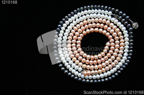 Image of Circle of white, black and pink pearls on the black background