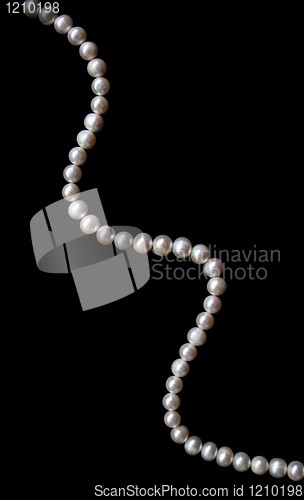 Image of White pearls on the black silk as background 