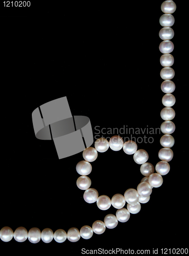 Image of White pearls on the black silk as background 