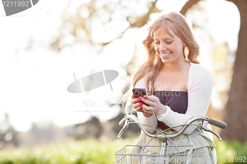 Image of Beautiful woman texting on her phone outdoor
