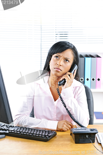 Image of Concerned black businesswoman on phone at desk