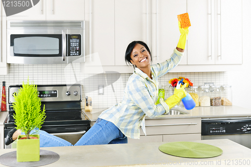 Image of Young woman cleaning kitchen