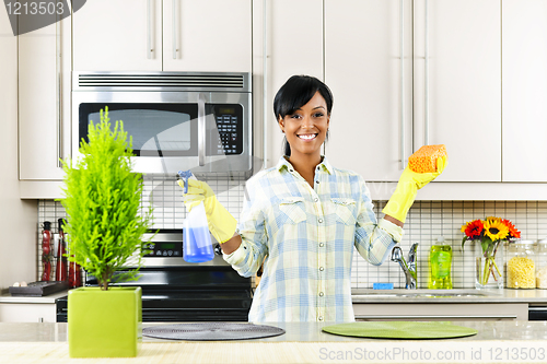 Image of Young woman cleaning kitchen