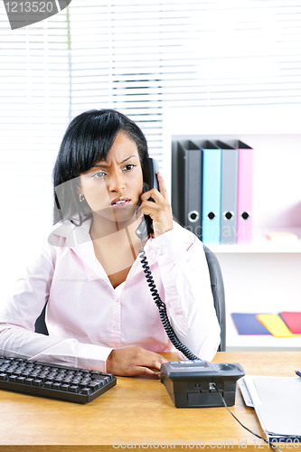 Image of Concerned black businesswoman on phone at desk