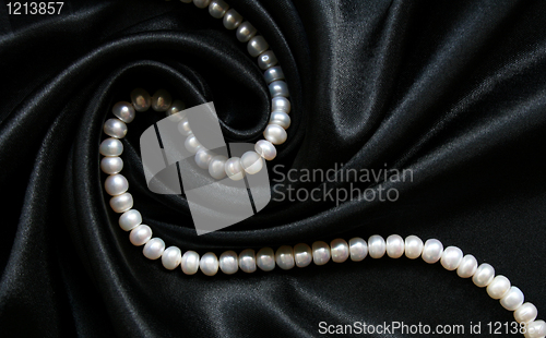 Image of White pearls on the black silk as background