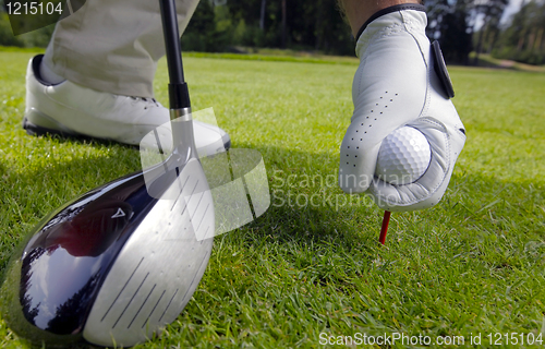 Image of hand placing a tee with golf ball 