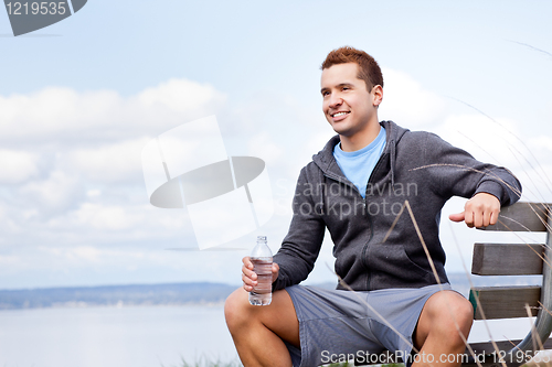 Image of Mixed race man holding water bottle