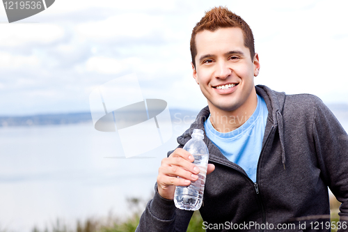 Image of Mixed race man holding water bottle