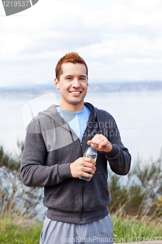 Image of Mixed race man holding water bottle