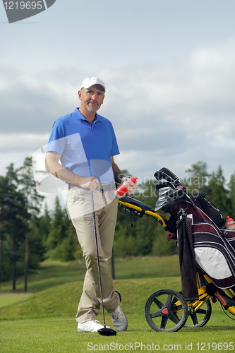 Image of Man standing by golf bag full of sticks 