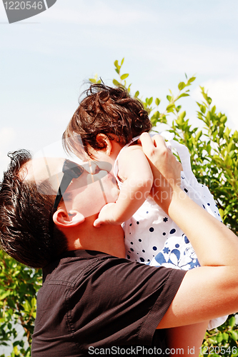 Image of father in early thirties gives his son a kiss on the cheek in the park 