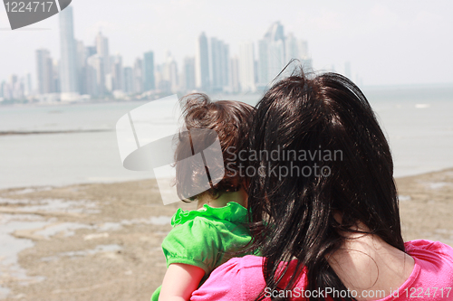 Image of Mother indicates her baby something interesting in sea 