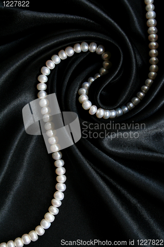 Image of White pearls on the black silk as background