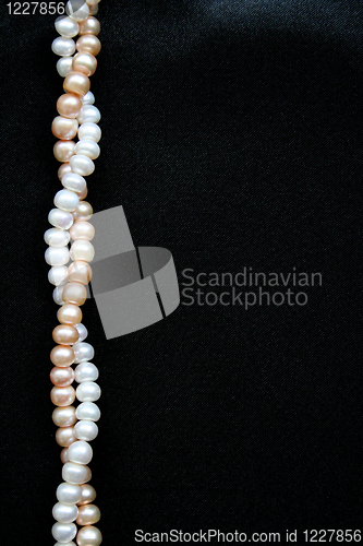 Image of White and pink pearls on the black silk background