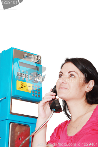 Image of young happy woman calling from public phone