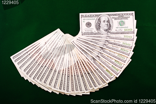 Image of A combination of dollar fan over a green background